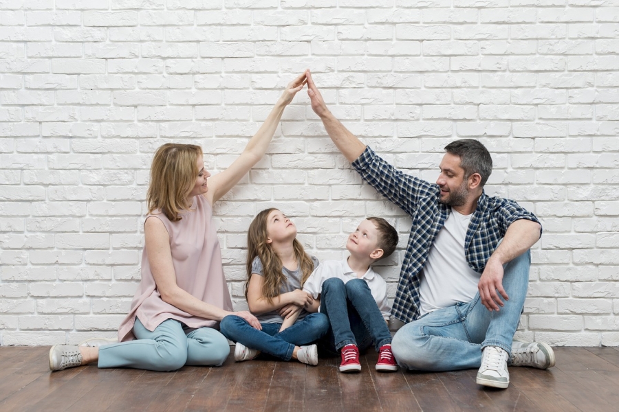 family sitting together in front of a white brick wall