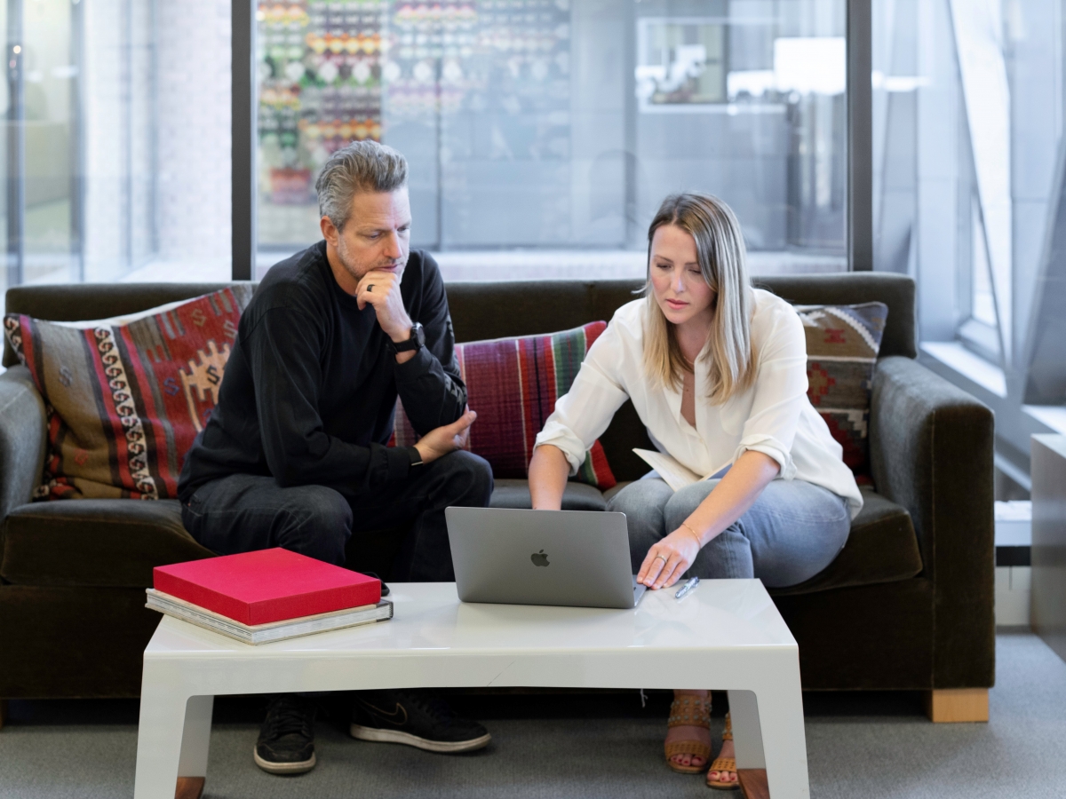 Man watching lady work on laptop