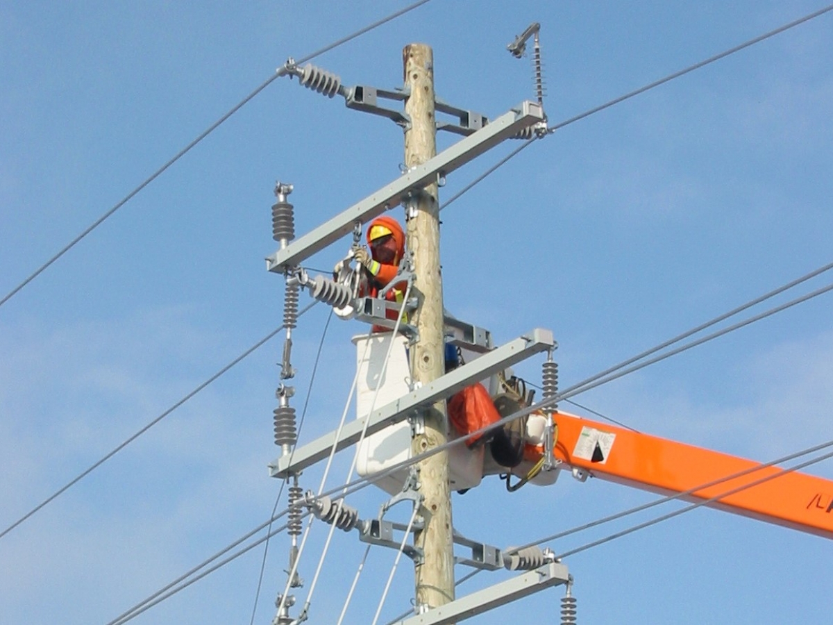 Man in orange working on the electrical lines